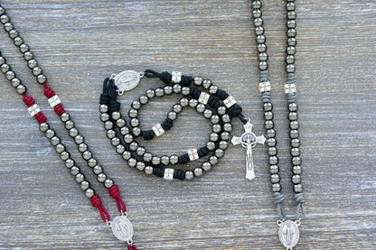 Last Stand Rosary: Gunmetal Hail Mary beads, silver Crusader Our Father beads, crimson, black, and iron gray paracord, crowned with a 2-inch St. Benedict crucifix and Miraculous Medal centerpiece.
