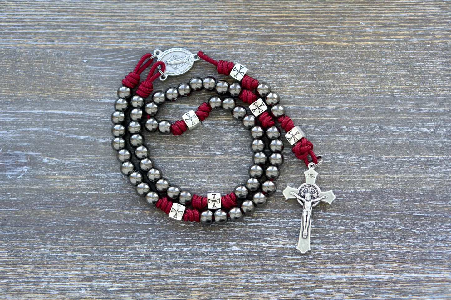 Last Stand Rosary: Gunmetal Hail Mary beads, silver crusader Our Father beads, Miraculous Medal centerpiece, and St. Benedict crucifix on red paracord.