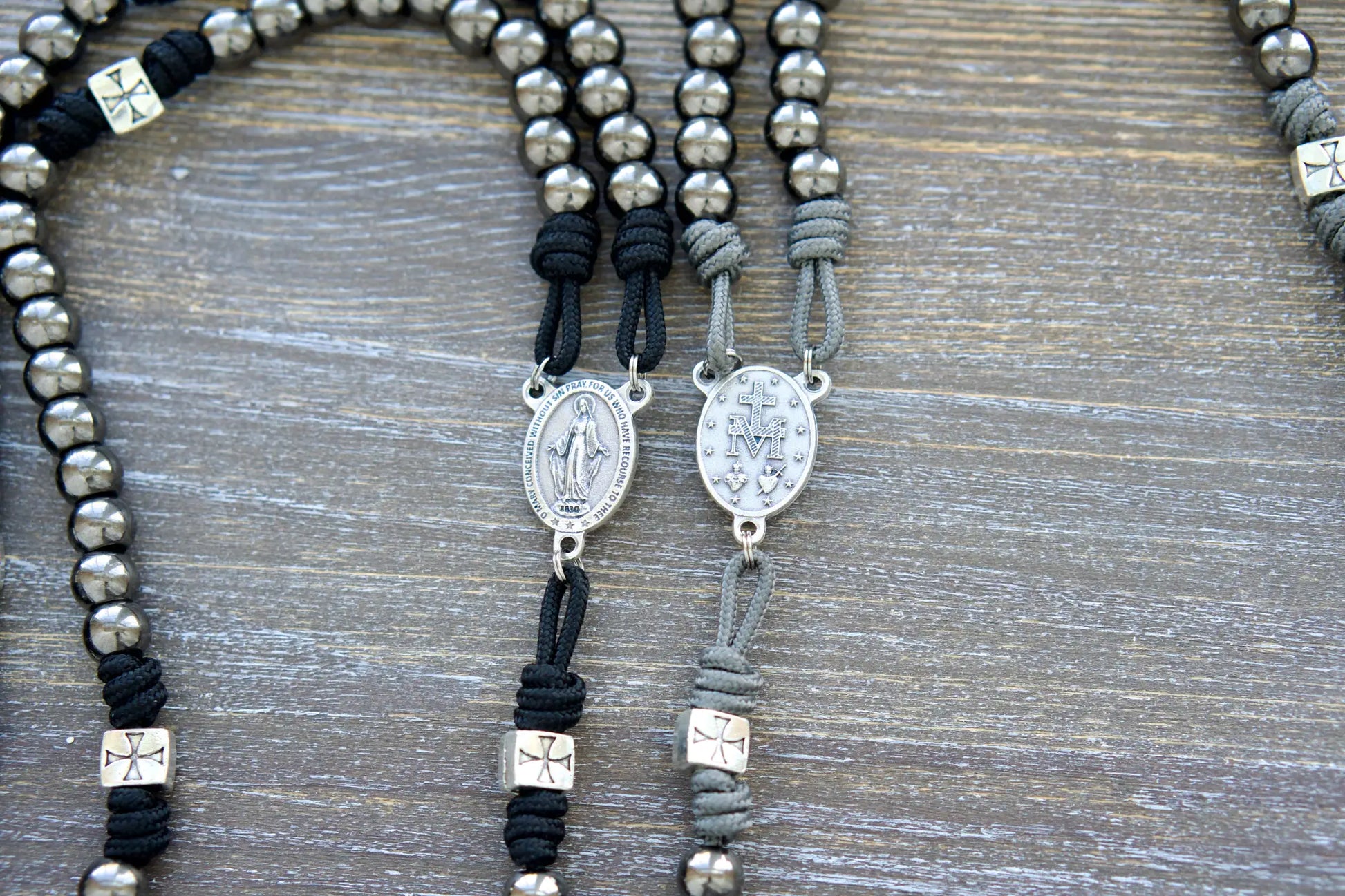 Last Stand Rosary: gunmetal Hail Mary beads, silver Crusader Our Father beads, Miraculous Medal centerpiece, and 2-inch St. Benedict crucifix on gray or black paracord.