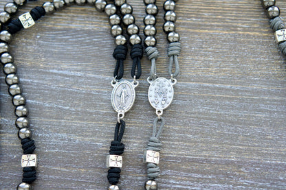 Last Stand Rosary: gunmetal Hail Mary beads, silver Crusader Our Father beads, Miraculous Medal centerpiece, and 2-inch St. Benedict crucifix on gray or black paracord.