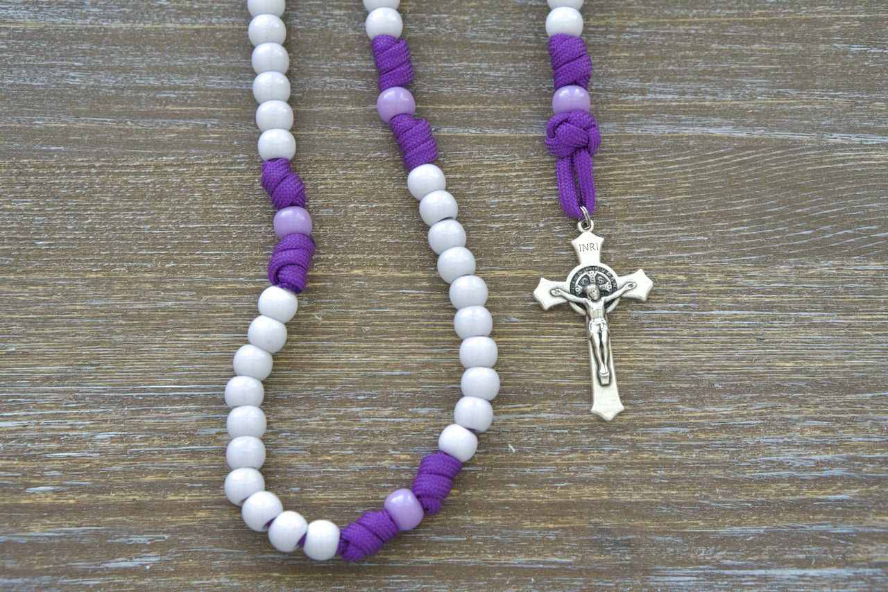 Little Flowers of Jesus Kid's Paracord Rosary, featuring durable purple paracord, light purple Our Father beads, white Hail Mary beads, 2-inch St. Benedict crucifix, and 0.75-inch Miraculous Medal, perfect for young Catholics and an ideal premium Catholic gift.