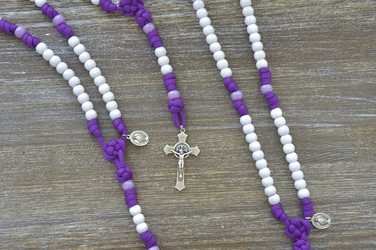 Little Flowers of Jesus - Kid's Paracord Rosary, featuring a durable purple paracord rope, light purple accent Our Father beads, white Hail Mary beads, and a 2-inch St. Benedict crucifix. Perfect Catholic gift for young kids.