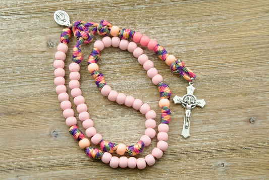  A colorful, fun, and durable kid's rosary designed for young girls, featuring light pink Hail Mary beads, a warm peach Our Father bead, and a smaller than normal Miraculous Medal. The unique pink camo paracord adds an adventurous touch to the design, perfect for little hands on-the-go.