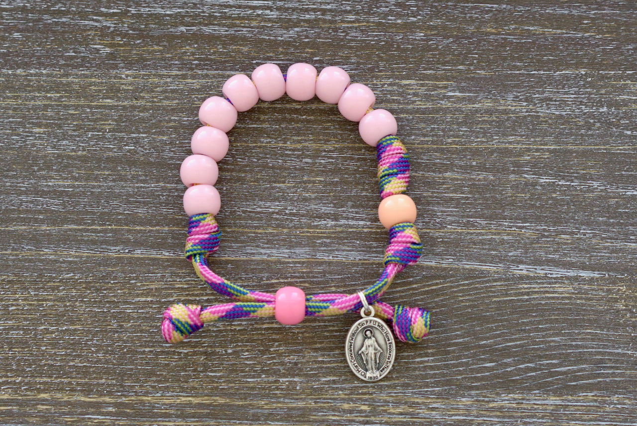 Little Lady's Miracle Kid's Rosary Bracelet - A vibrant and durable pink, green, and orange paracord bracelet adorned with petite 10mm pink beads symbolizing Hail Mary prayers and matching orange Our Father beads.