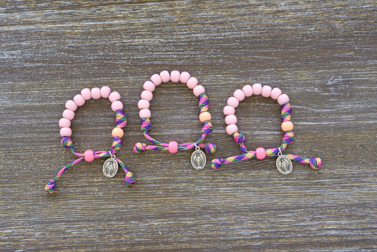 Little Lady's Miracle - Kid's Rosary Bracelet, a colorful paracord rosary bracelet featuring petite pink beads for Hail Mary prayers and matching orange Our Father beads, adorned with a tiny Miraculous Medal charm.