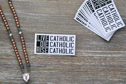 Live Catholic. Die Catholic. Rise Catholic. vinyl sticker featuring bold text inspired by Scripture (2 Timothy 4:7-8, John 11:25-26, Revelation 14:13), measuring 4.5" wide x 2.25" tall. Removable, matte laminated white vinyl with UV resistance for indoor/outdoor use on various surfaces.