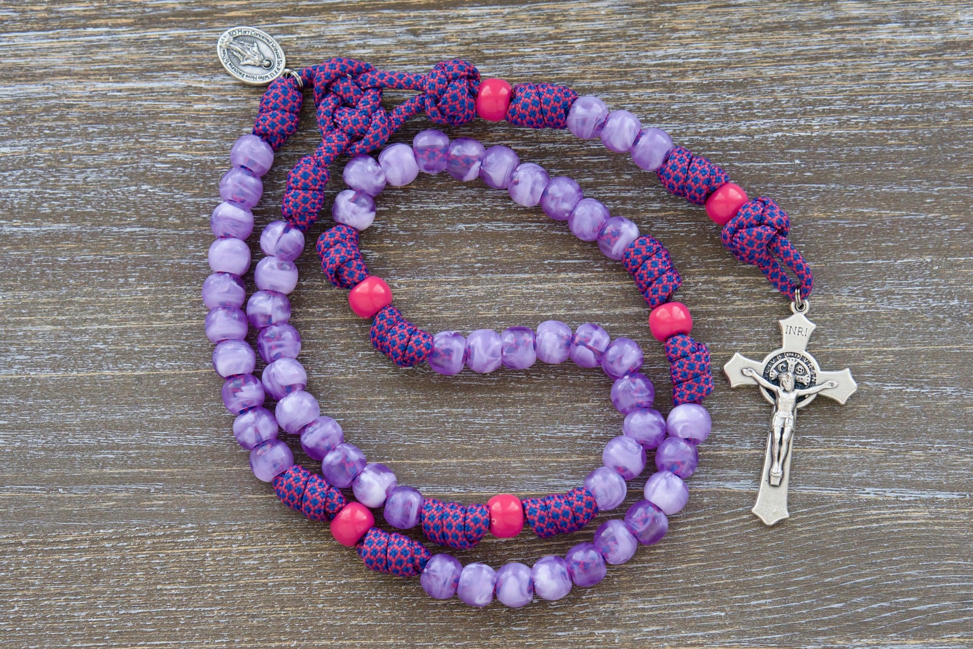 Vibrant pink and milky purple paracord rosary designed for children, featuring a smaller 3/4 inch Miraculous Medal and a 2-inch St. Benedict crucifix.  Crafted with durable 10mm acrylic beads, the "Maiden of Faith" rosary is a spiritual weapon for young Catholic girls.