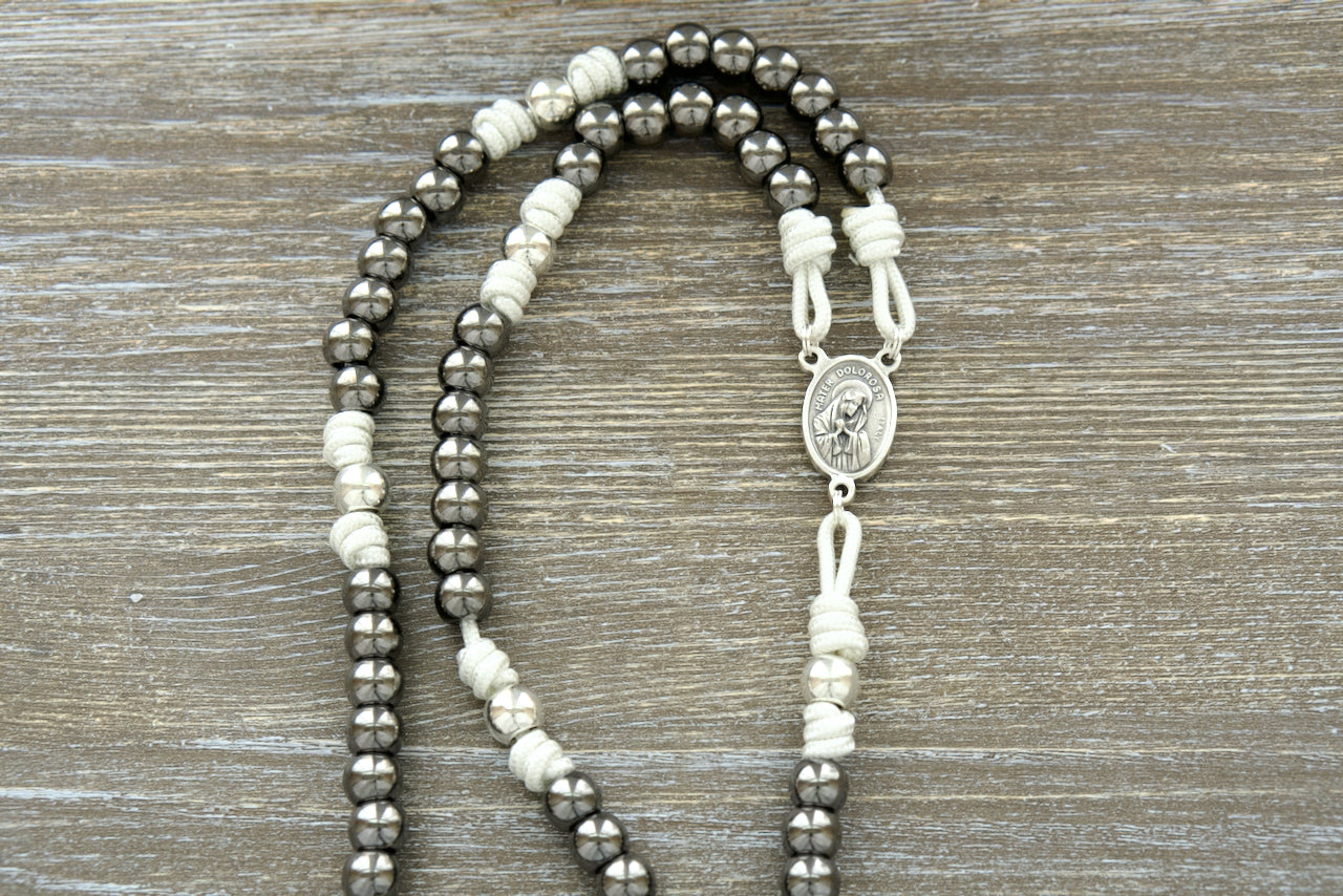 Beautiful white paracord 7 Sorrows Servite Rosary with silver and gunmetal beads, featuring the Mater Dolorosa/Ecce Homo centerpiece and a 2" Pardon Crucifix. Premium Catholic rosary chaplet for spiritual growth and contemplation.