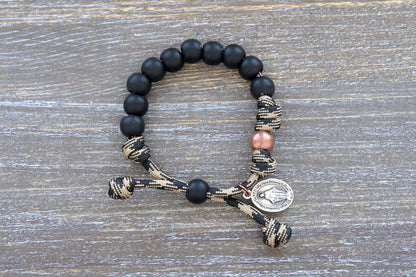 Mini Duty Hail Mary kids bracelet features rugged 10mm matte black beads, an antique copper Our Father bead, and a small Miraculous Medal on durable paracord.