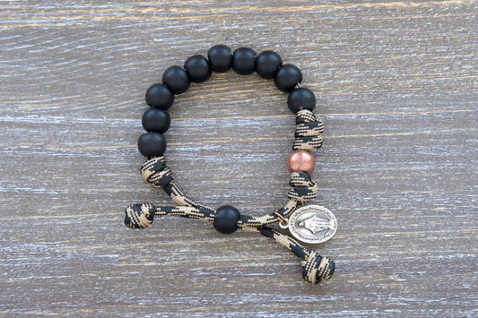 Mini Duty Hail Mary kids bracelet features rugged 10mm matte black beads, an antique copper Our Father bead, and a small Miraculous Medal on durable paracord.