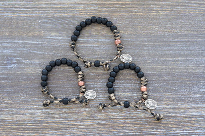 This mini duty rosary bracelet features 10mm matte black Hail Mary beads, an antique copper Our Father bead, and a sacred Miraculous Medal on rugged paracord.