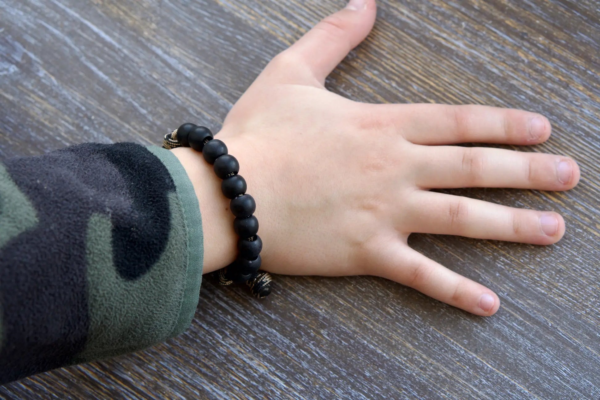 Rugged black acrylic rosary bracelet for kids featuring a Miraculous Medal and antique copper Our Father bead on durable paracord.