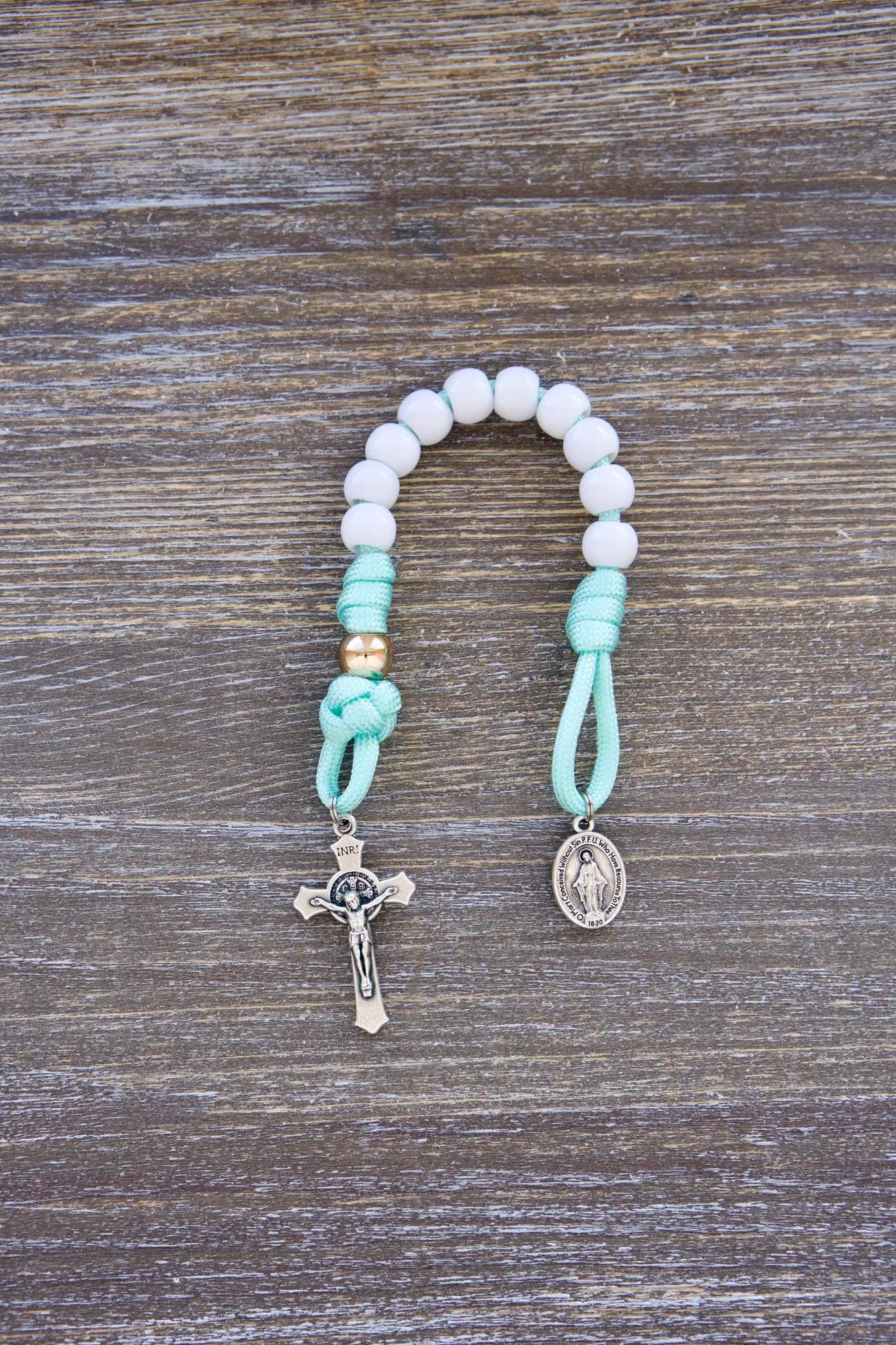 Mint green paracord rosary with white Hail Mary and rose gold Our Father beads, 10mm acrylic beads, Miraculous Medal, and St. Benedict crucifixes.