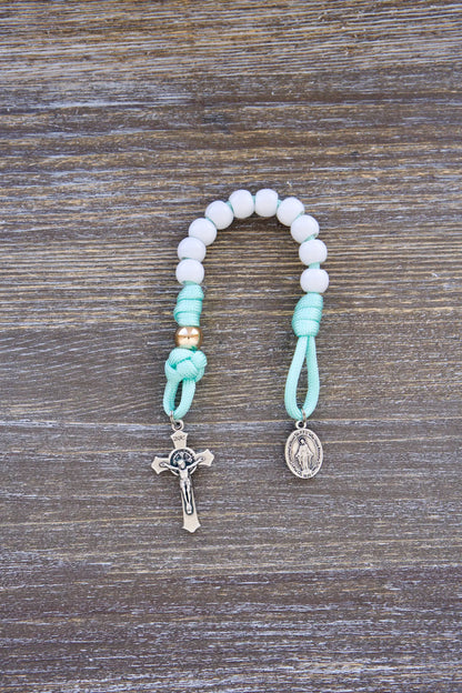 Mint green paracord rosary with white Hail Mary and rose gold Our Father beads, 10mm acrylic beads, Miraculous Medal, and St. Benedict crucifixes.