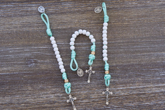 Mint green paracord rosary with white Hail Mary and rose gold Our Father beads, featuring small Miraculous Medal and St. Benedict crucifixes.