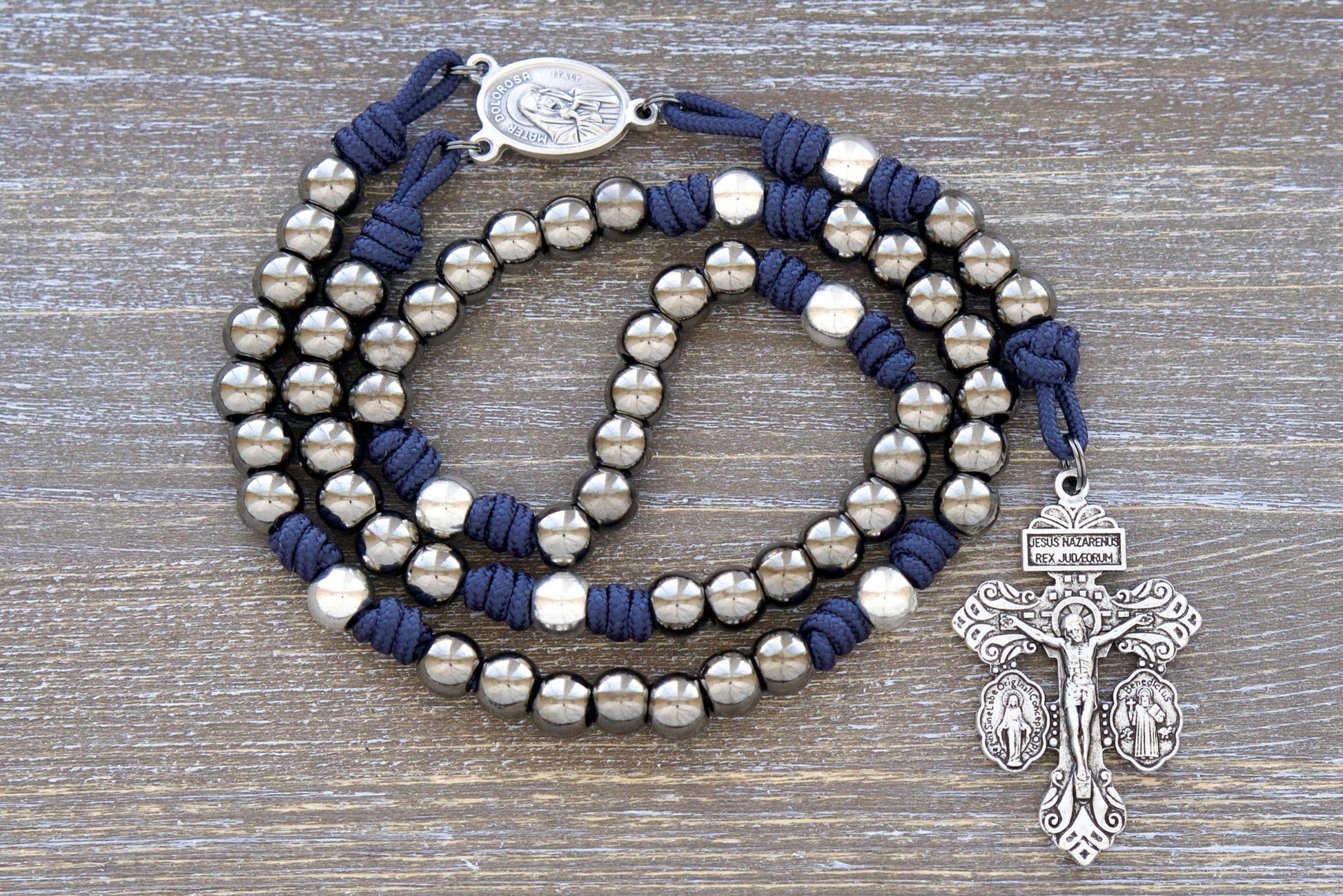 Navy blue paracord Servite Rosary chaplet featuring silver and gunmetal metal alloy beads, Mater Dolorosa/Ecce Homo centerpiece medal, and a triple crucifix.  Handmade with premium materials for enduring spiritual devotion.