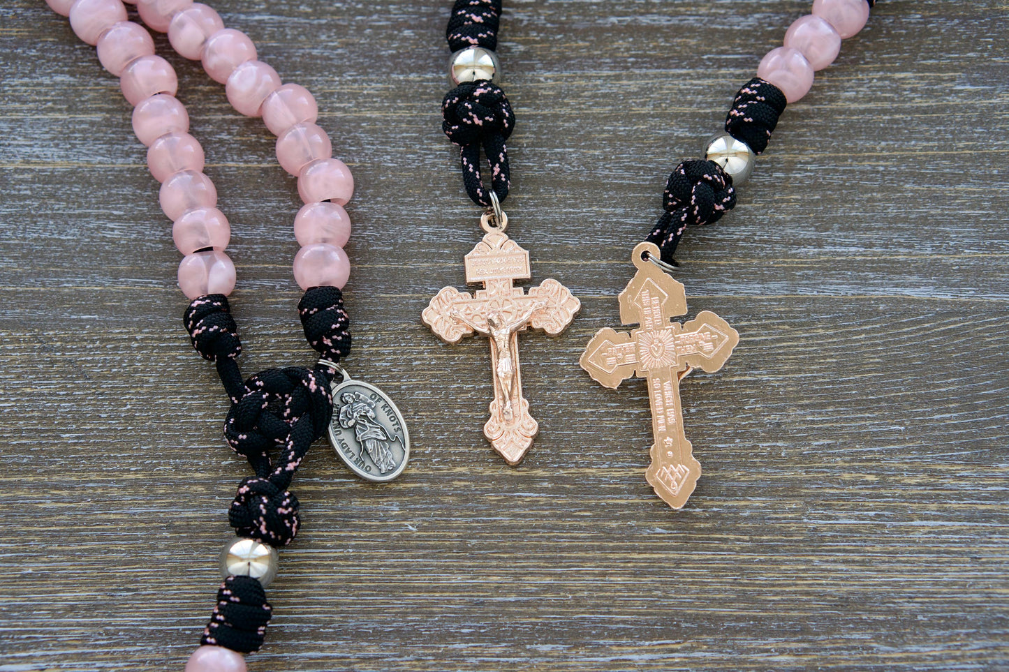 Our Lady Untier of Knots 5 Decade Paracord Rosary - Features pink acrylic gemstone Hail Mary beads, silver Our Father beads, black and pink paracord, and an exclusive rose gold pardon crucifix. Includes the devotional medal of Our Lady Untier of Knots.