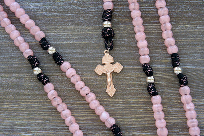 Our Lady Untier of Knots 5 Decade Paracord Rosary:  Pink acrylic gemstone Hail Mary beads, shiny silver Our Father beads, black and pink paracord interwoven with a devotional medal of Our Lady Untier of Knots, topped with an exclusive rose gold pardon crucifix.