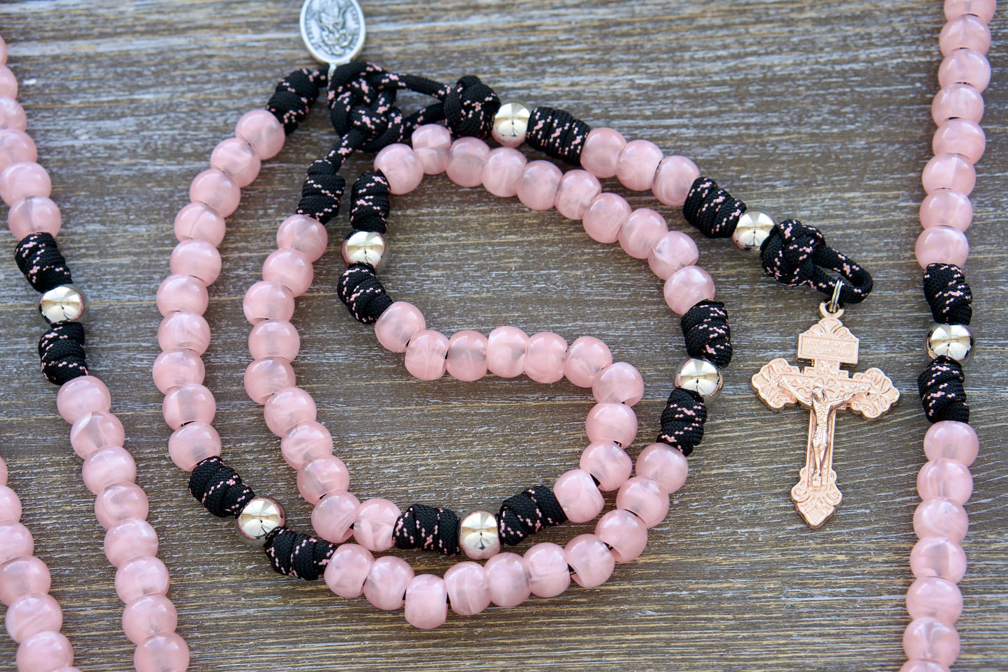 Our Lady Untier of Knots 5 Decade Paracord Rosary: Shiny silver & pink acrylic gemstone beads on black paracord with devotional medal and exclusive rose gold pardon crucifix.