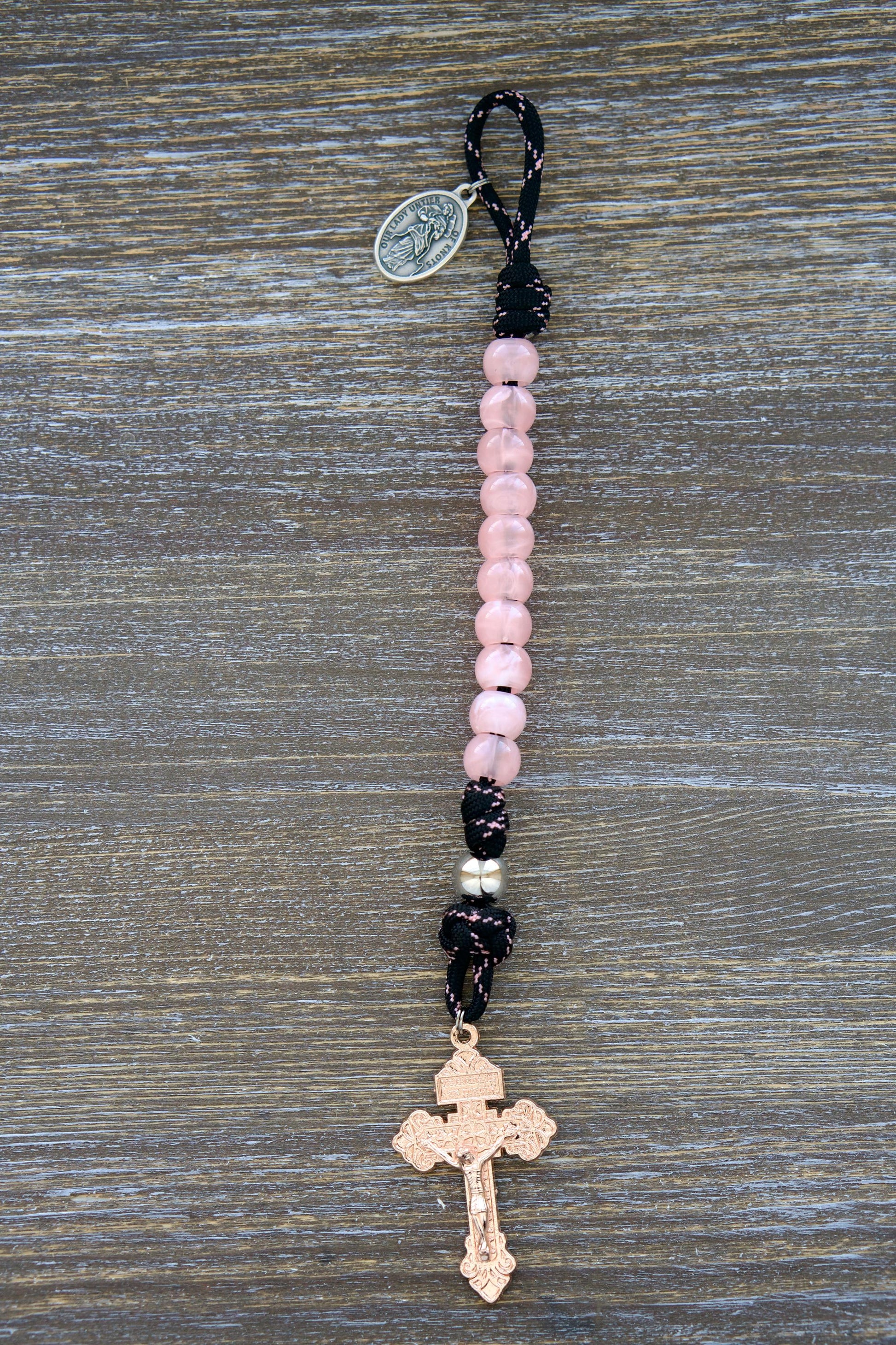 Exquisite single decade Our Lady Untier of Knots pocket paracord rosary with pink acrylic Hail Mary beads, silver Our Father bead, black paracord accented with pink, devotional medal, and unique rose gold pardon crucifix.