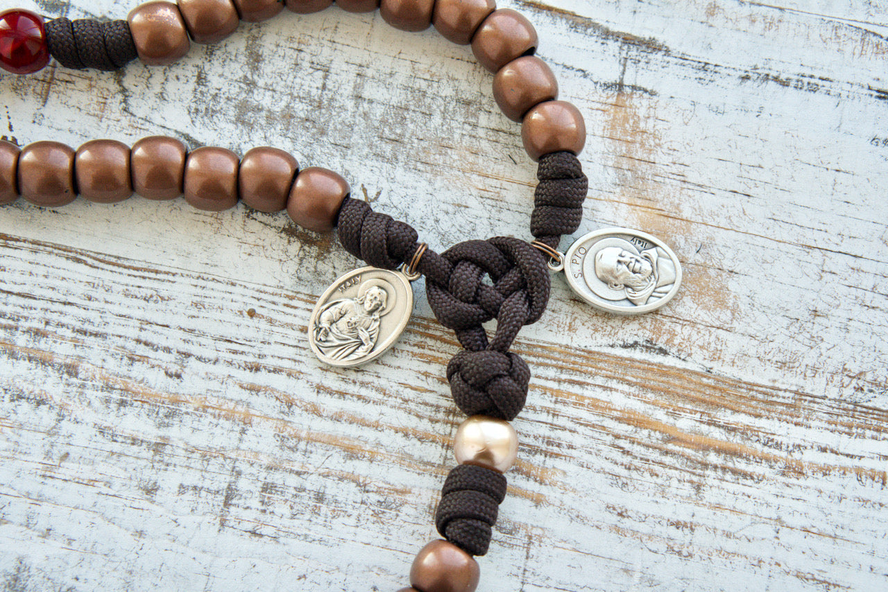 St. Padre Pio's Intercession - 5 Decade Paracord Rosary, featuring maroon red beads for Stigmata wounds, antique copper Hail Mary beads, devotional medals, and a heavy duty copper Crucifix. Perfect for deepening faith and making Catholic gifts.