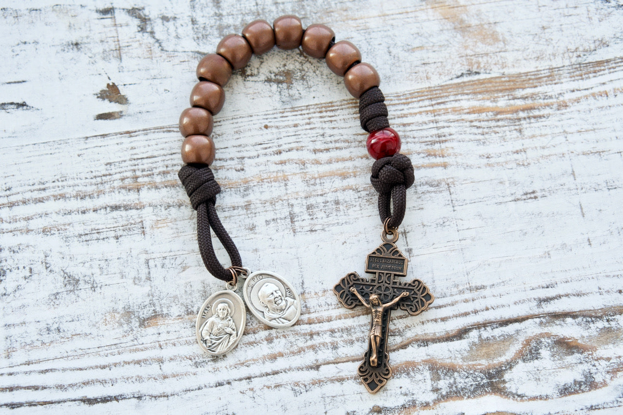 St. Padre Pio's Intercession - 1 Decade Paracord Rosary in brown, red and antique copper, featuring devotional medals, a deep maroon Stigmata Our Father bead, and a standard size copper Pardon Crucifix. Perfect for deepening faith and making a special Catholic gift.