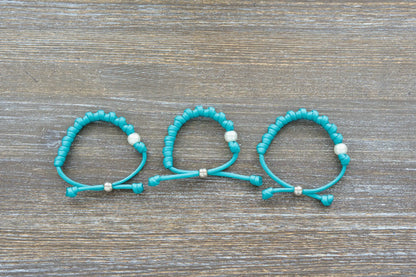 Teal blue paracord 550 knotted rosary bracelet features a white Our Father bead, silver accent, perfect for adults.