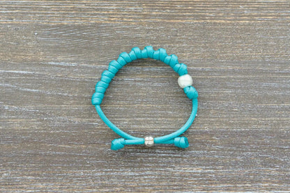 Hand-knotted teal blue paracord rosary bracelet features a white Our Father bead, silver tie bead.