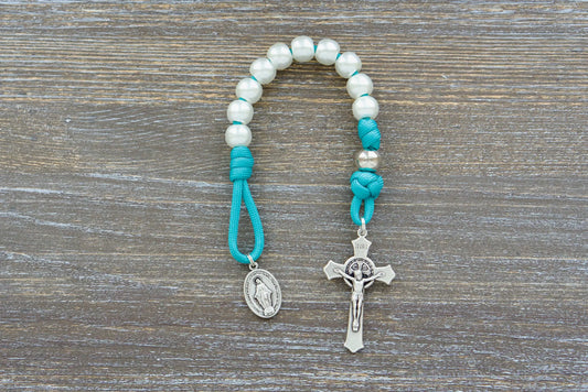 Teal blue paracord rosary with pearl white Hail Mary beads, silver Our Father beads, St. Benedict Crucifix, and Miraculous Medal.