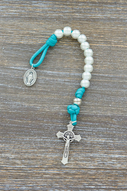 Peaceful Waters Pocket Paracord Rosary in teal blue with pearl and silver beads, silver Our Father beads, St. Benedict crucifix, and Miraculous Medal.