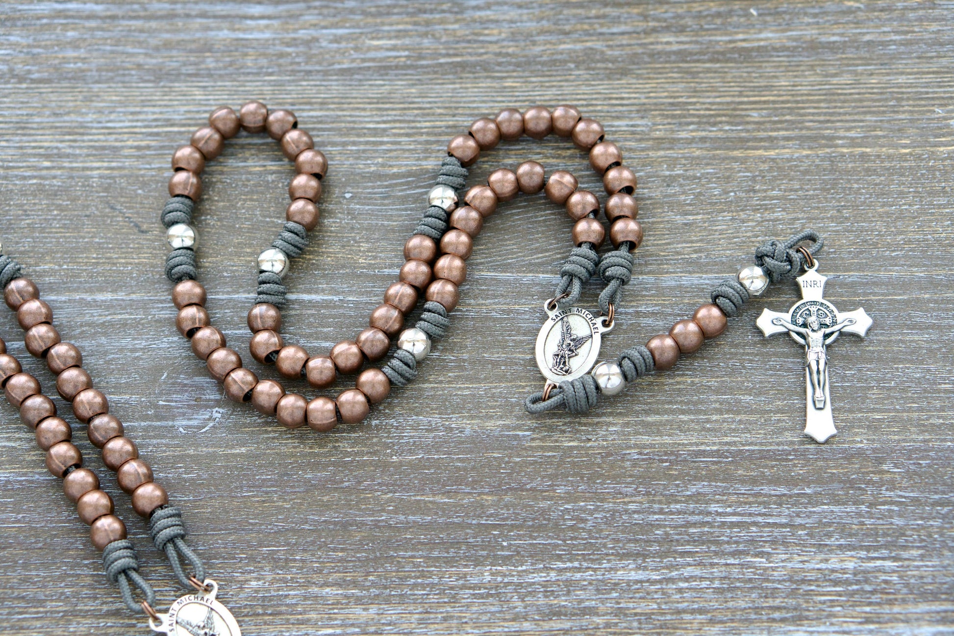 Premium Metal Paracord Rosary featuring rugged grey paracord, alloy metal Hail Mary beads, silver Our Father beads, silver St. Michael centerpiece devotional medal, and a 2-inch St. Benedict crucifix.