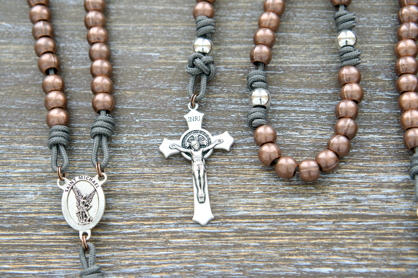 Premium metal paracord rosary in grey hue with alloy metal Hail Mary beads, silver Our Father beads, and silver St. Michael centerpiece & crucifix. Perfect for spiritual protection and devotion.