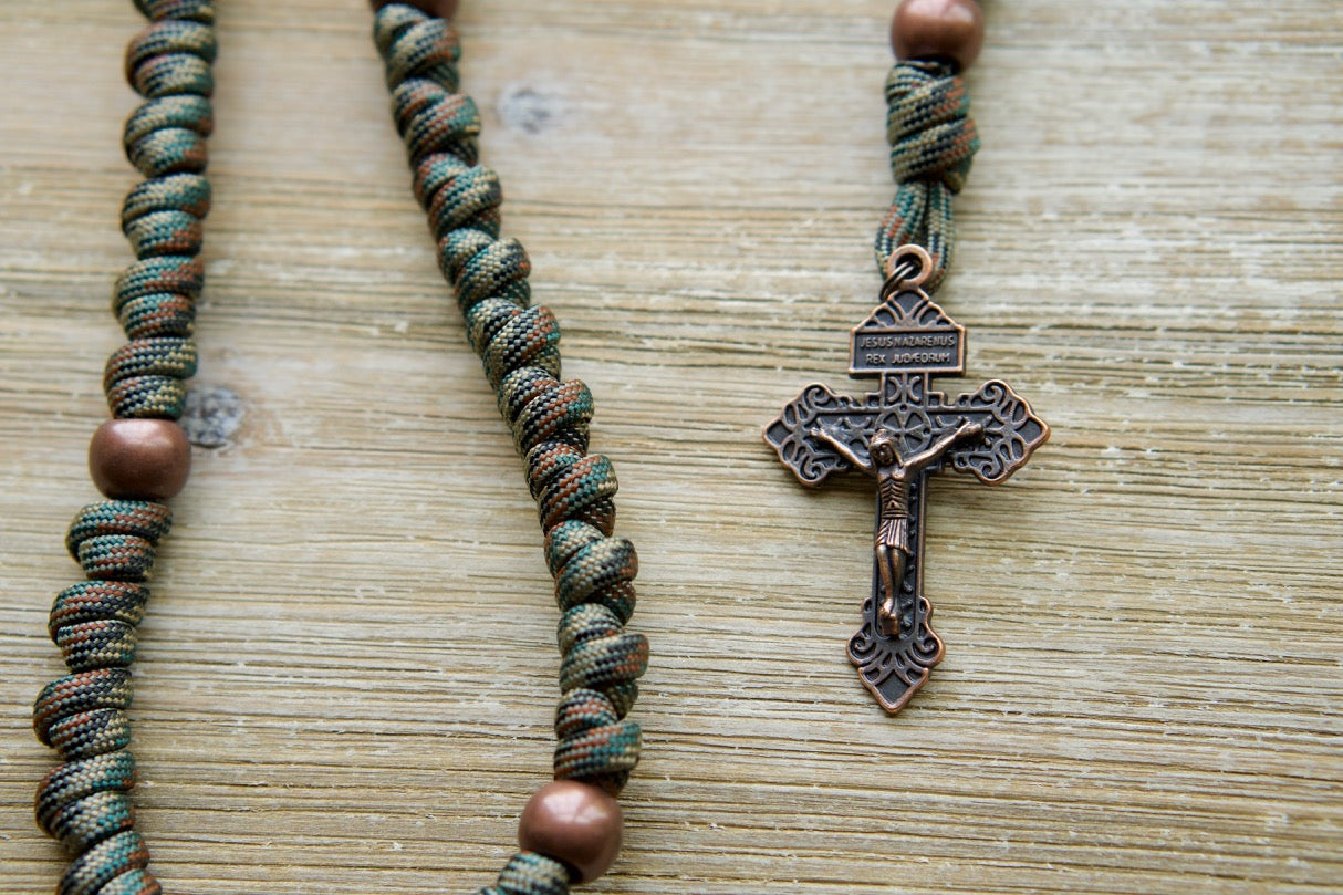 The Serpent Slayer - Camo and Copper Knotted Rope Rosary, your unbreakable spiritual weapon against evil. Featuring 19 inches of durable Paracord 550 rope, a bold camouflage and copper design, an antique copper Pardon Crucifix, and a St. Benedict devotional medal.