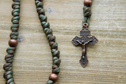 The Serpent Slayer - Camo and Copper Knotted Rope Rosary, your unbreakable spiritual weapon against evil. Featuring 19 inches of durable Paracord 550 rope, a bold camouflage and copper design, an antique copper Pardon Crucifix, and a St. Benedict devotional medal.