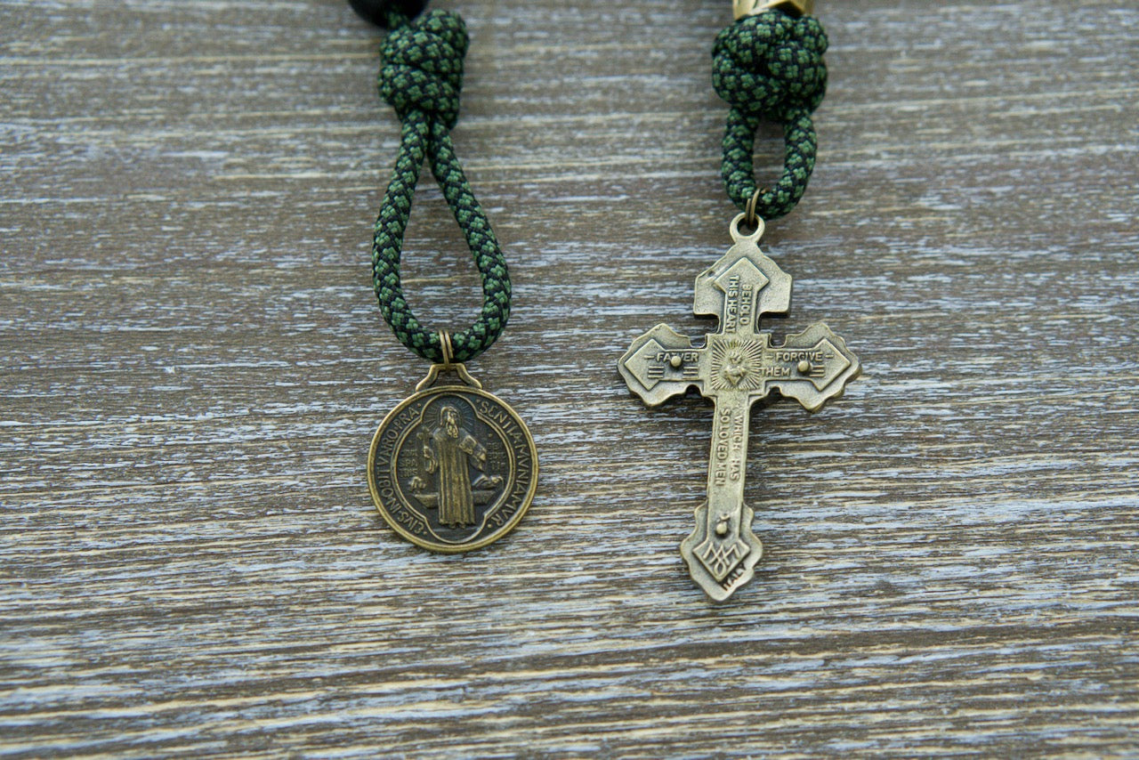 Sanctus Servo's Shield of Faith - Green, Black and Olive 1 Decade Paracord Rosary featuring durable green camo rope with 12mm matte black Hail Mary beads, unique bronze Crusader cross Our Father beads, a bronze 2" Pardon Crucifix, and a bronze devotional St. Benedict medal for spiritual strength on your faith journey.