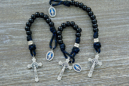 Embrace the unwavering devotion of The Solemn Crusader - Blue Black and Silver 1 Decade Paracord Rosary. Crafted with durable black paracord, shiny black Hail Mary beads, and a noble silver crusader Our Father bead, this premium Catholic gift is designed to withstand life's battles while honoring the traditions of your faith.