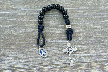 Embrace unwavering devotion with the Solemn Crusader - Blue Black and Silver 1 Decade Paracord Rosary. Handcrafted by our Catholic family for strength, grace, and resilience in faith. Durable paracord, shiny black beads, silver crusader Our Father beads, and a protective St. Benedict crucifix make this rosary an unbreakable spiritual weapon. 