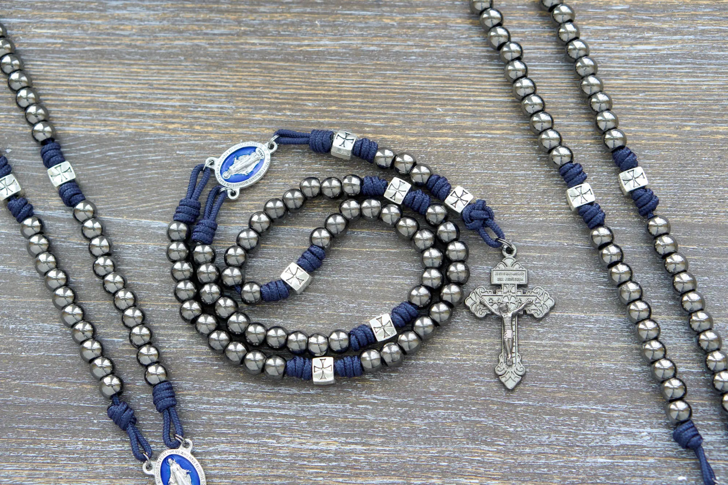 Silver crusader Our Father beads and gunmetal Hail Mary beads adorn The Solemn Crusader metal paracord rosary, featuring a blue enamel Miraculous Medal centerpiece.