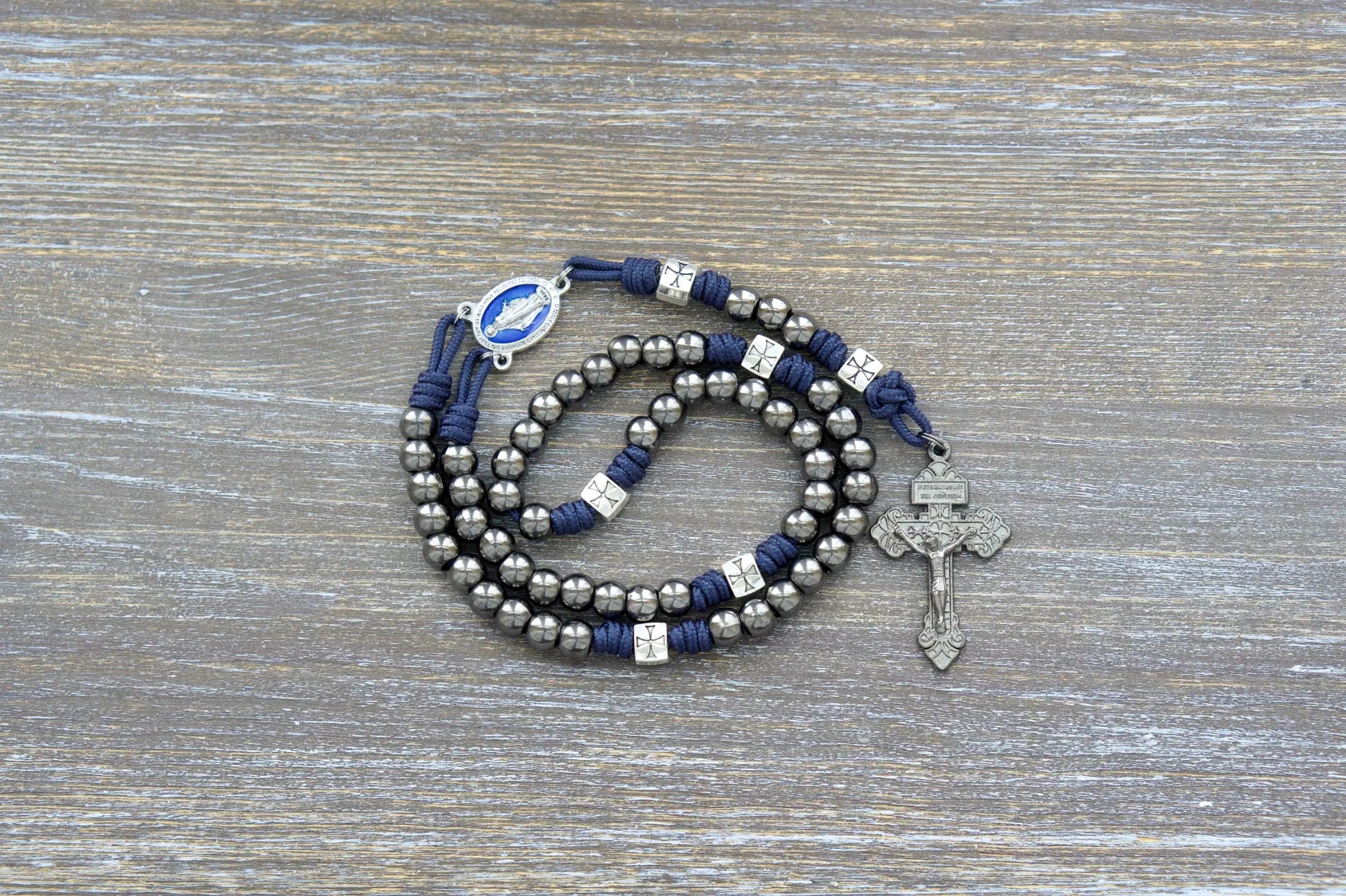 Solemn Crusader Rosary: Navy blue paracord with silver crusader Our Father beads, gunmetal Hail Mary beads, and blue enamel Miraculous Medal centerpiece.