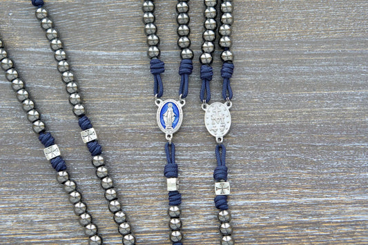 The Solemn Crusader: navy blue paracord rosary with silver crusader Our Father beads, gunmetal Hail Mary beads, and a blue enamel Miraculous Medal centerpiece.
