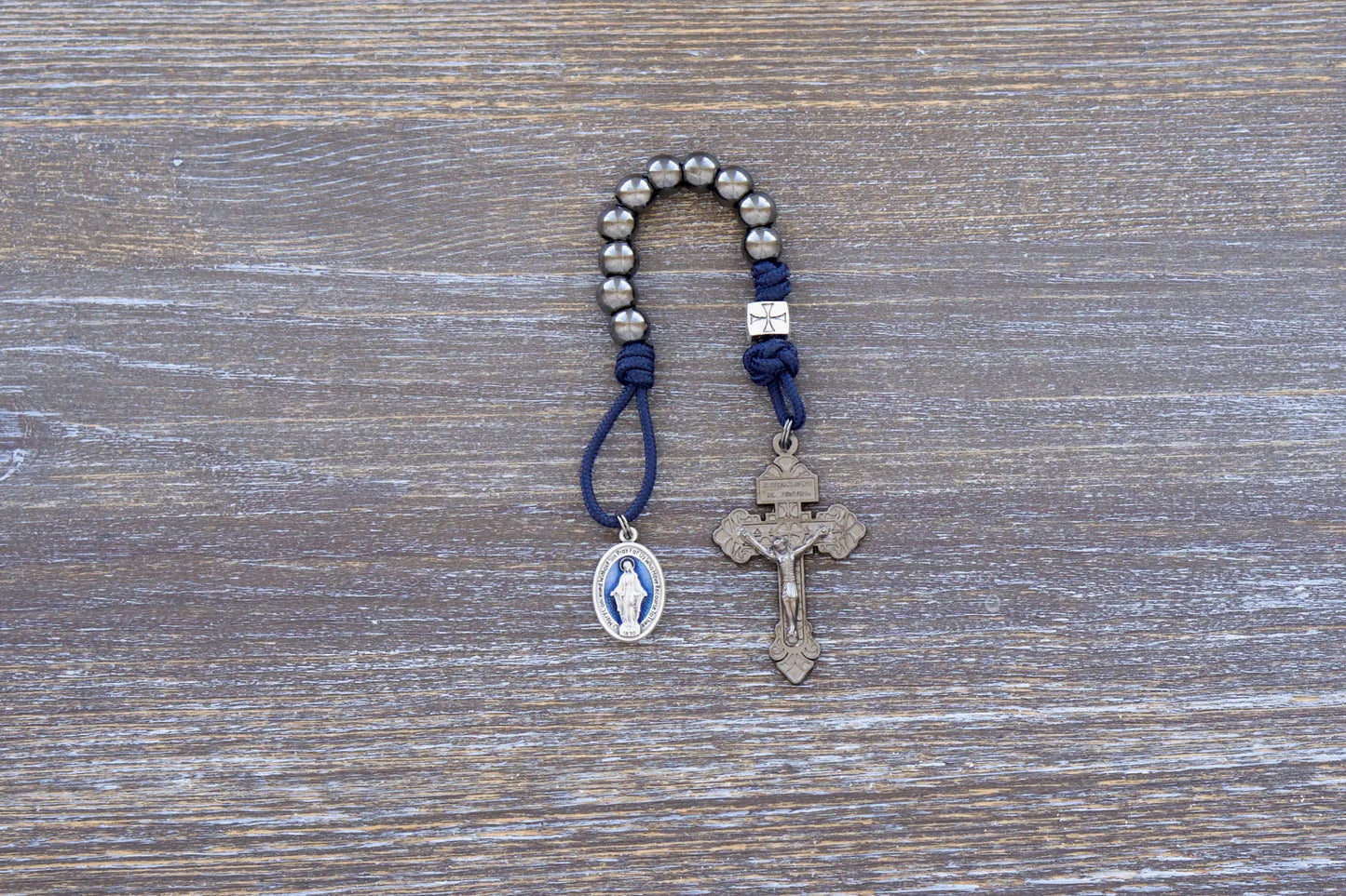 Solemn Crusader pocket paracord rosary with gunmetal metal alloy beads, blue enamel Miraculous Medal, and silver crusader Our Father.