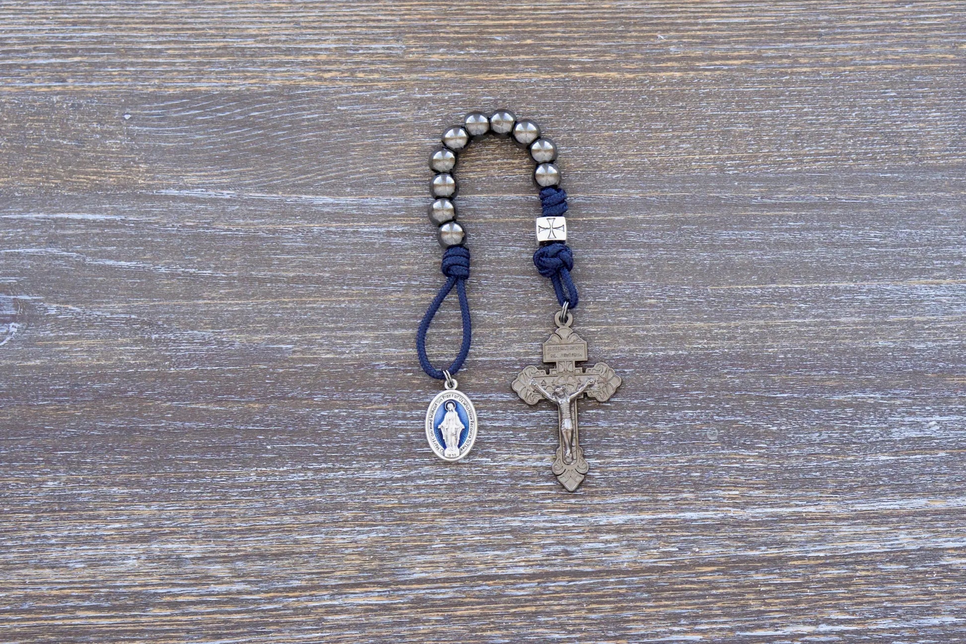 Solemn Crusader pocket paracord rosary with gunmetal metal alloy beads, blue enamel Miraculous Medal, and silver crusader Our Father.