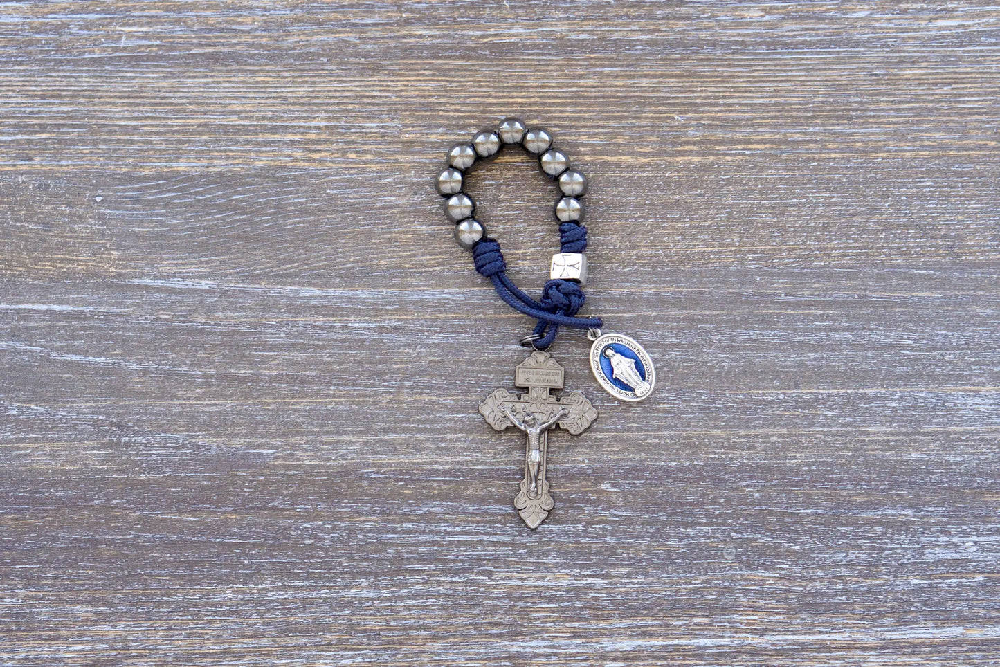 Solemn Crusader paracord rosary with silver Our Father bead, gunmetal Hail Mary beads, and blue enamel Miraculous Medal centerpiece.