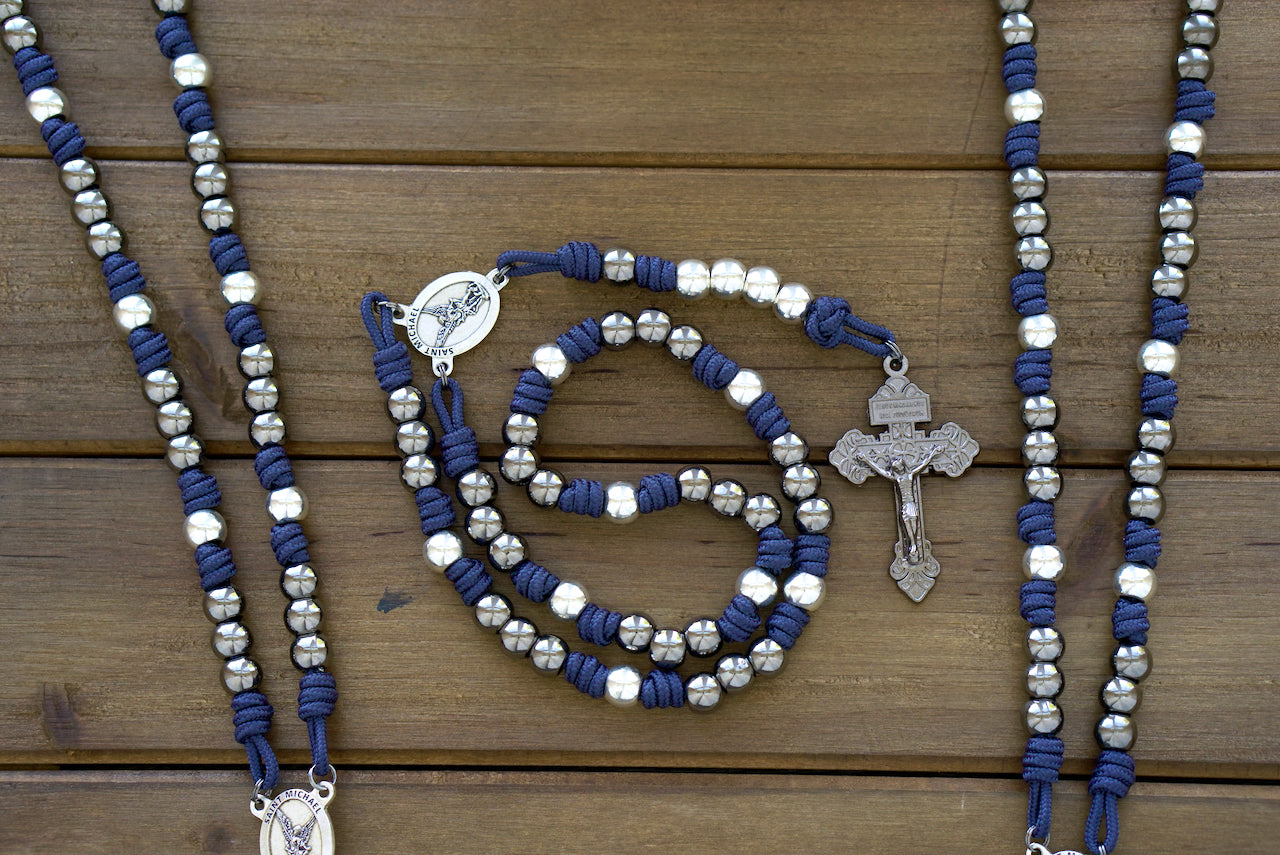 St. Michael Chaplet: Navy blue paracord chaplet with gunmetal-toned 10mm metal alloy beads, featuring a striking silver St. Michael medal centerpiece and a Pardon crucifix. Handmade rosary designed for durability and prayerful contemplation.