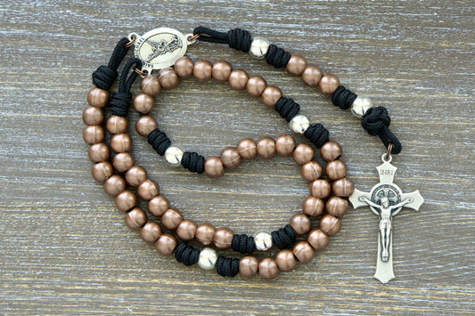 Premium paracord rosary featuring durable 275 paracord in grey, black, green, or navy blue. Highlights include copper Hail Mary beads, silver Our Father beads, a radiant St. Michael centerpiece medal, and a 2-inch St. Benedict crucifix