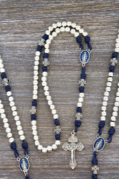 Premium navy blue paracord Rosary, Stella Maris,  featuring shiny silver metal alloy Hail Mary beads, cross-shaped Our Father beads, a blue enamel Miraculous Medal centerpiece, and a matching silver 2" Pardon Crucifix.