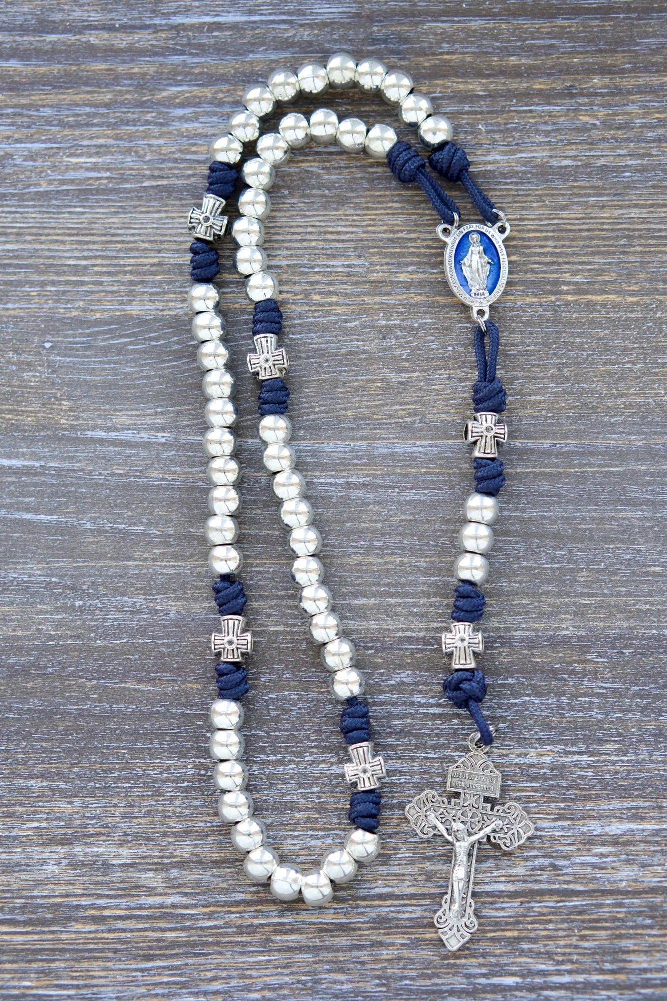 Stella Maris Rosary: Navy blue paracord with silver metal Hail Mary and cross-shaped Our Father beads, accented by a blue enamel Miraculous Medal and silver Pardon Crucifix.