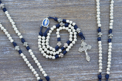 Navy blue paracord Stella Maris rosary with shiny silver metal alloy Hail Mary and cross-shaped Our Father beads, featuring a blue enamel Miraculous Medal and silver Pardon crucifix.