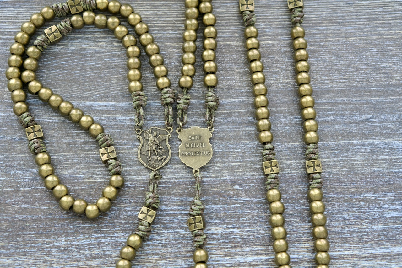 The Strength of the Militant Holy Rosary, a Premium Metal Paracord Rosary with olive green camo paracord, featuring durable alloy metal Crusader beads and a St. Michael centerpiece medal, perfect for Catholics seeking spiritual strength in their ongoing battle against evil.