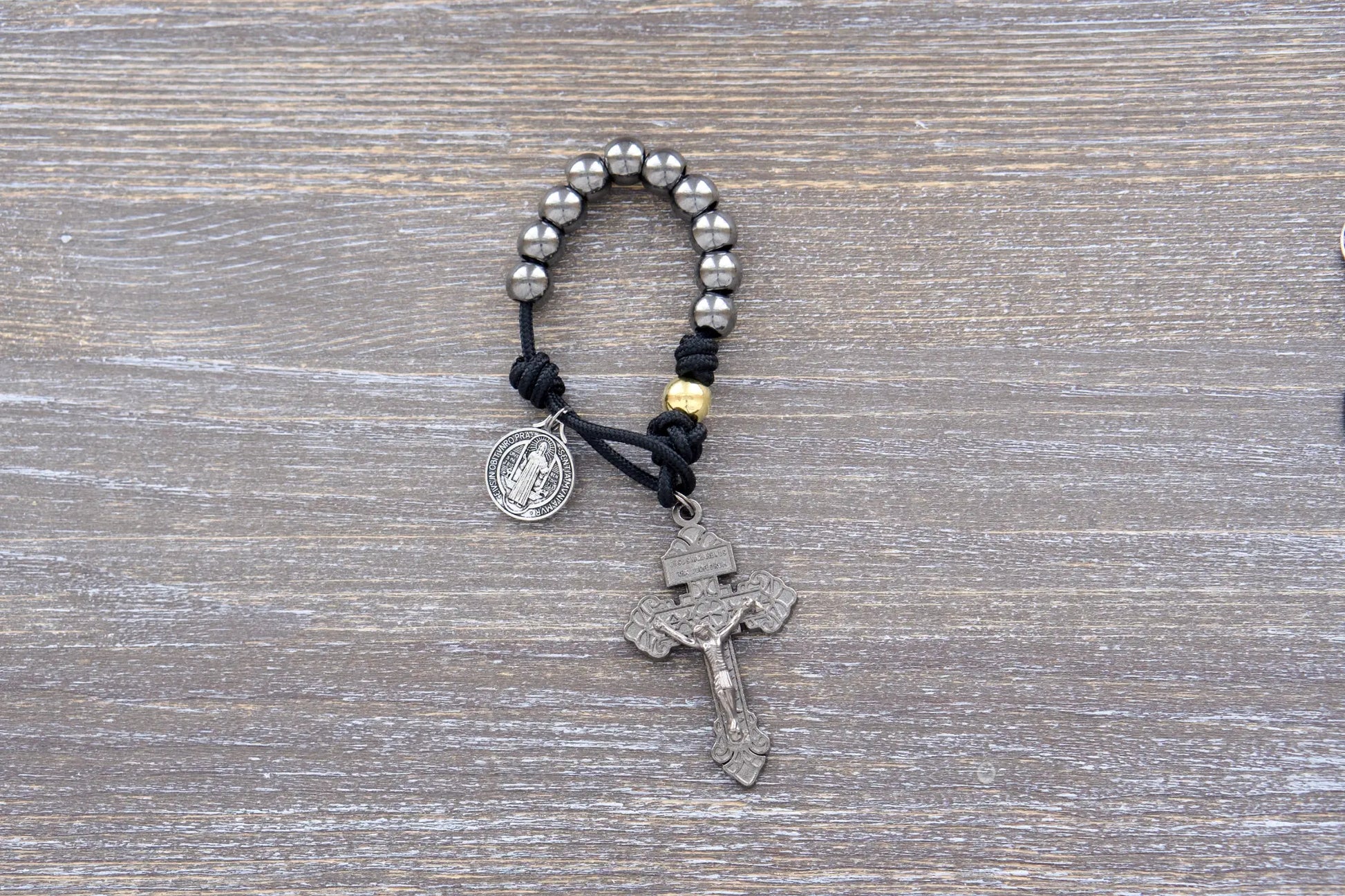 Stronghold of pocket Grace paracord rosary with 10mm gunmetal Hail Mary beads, gold Our Father beads, and 2-inch Pardon crucifix